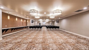 A conference room with rows of chairs, a long table, and a projector screen at the front.