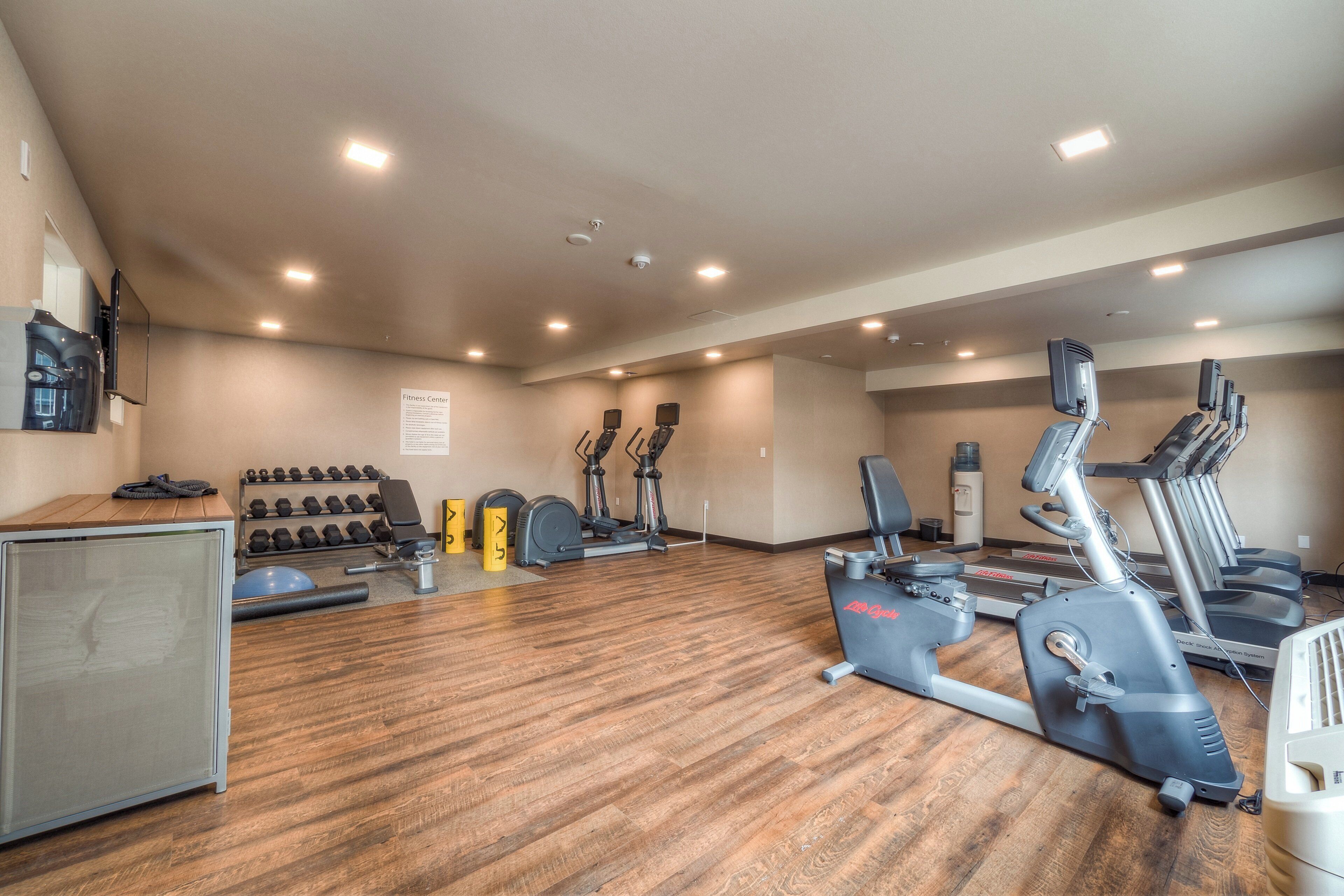 Un gimnasio con cintas de correr, elípticas y pesas sueltas.