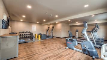 Un gimnasio con cintas de correr, elípticas y pesas sueltas.