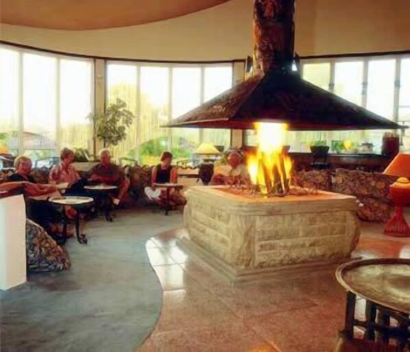 A lobby with a central stone fireplace, seating areas, and large windows. - Lycus River Thermal Hotel (Denizli)