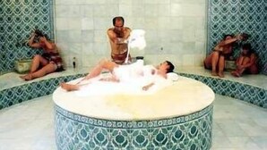A circular hot tub with a person standing and another lying inside, surrounded by patterned walls. - Lycus River Thermal Hotel (Denizli)