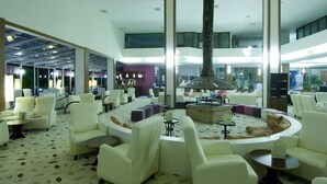 A spacious lobby with a central seating area, a fireplace, and a high ceiling with skylights. - Lycus River Thermal Hotel (Denizli)