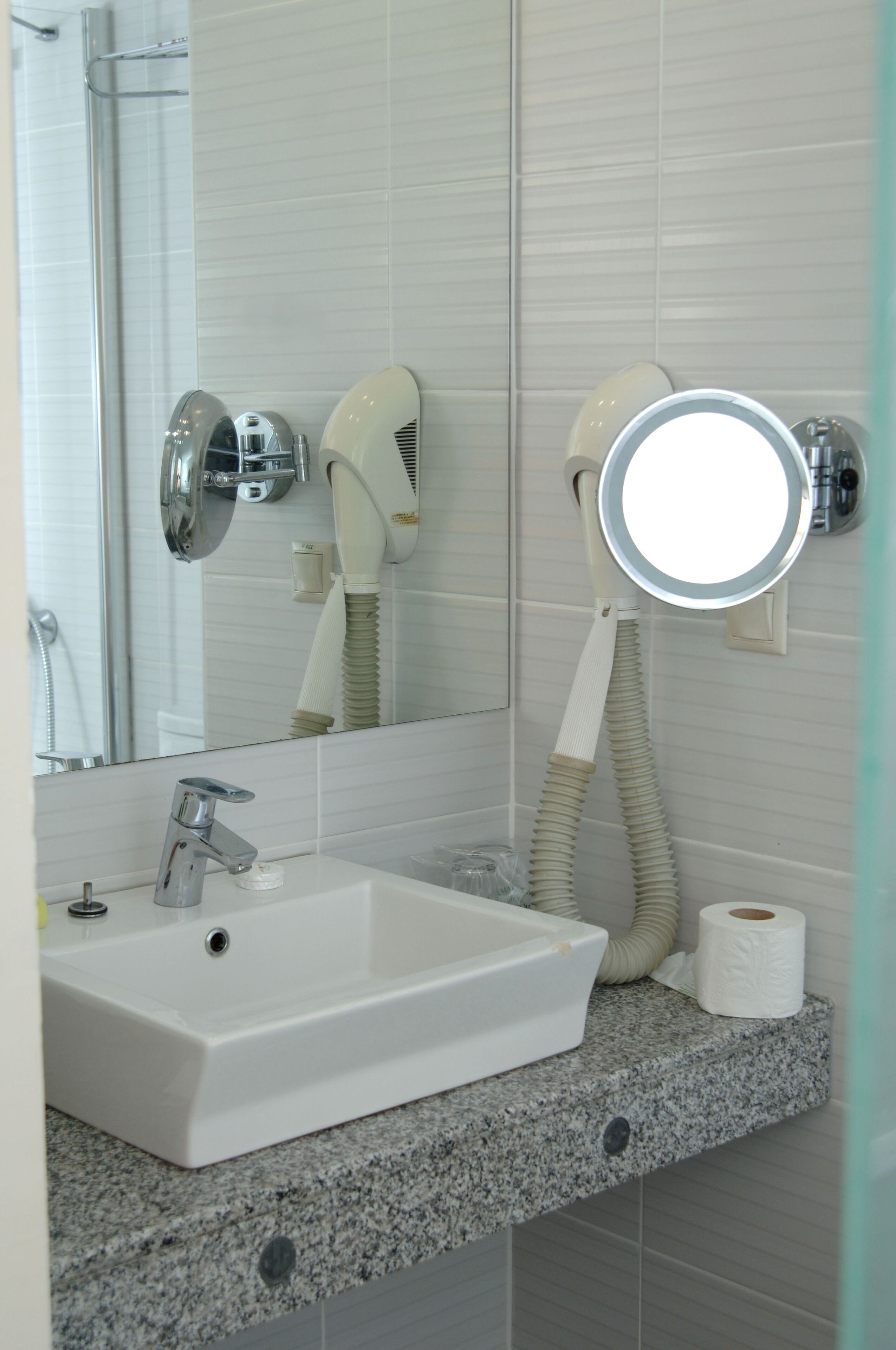 A bathroom with a white sink, a mirror, a hairdryer, and a towel rack.