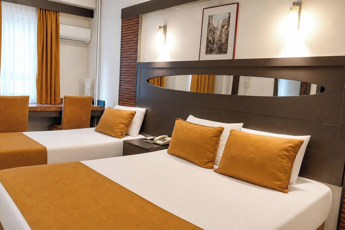 A hotel room with two beds, a desk, a chair, and a large mirror.