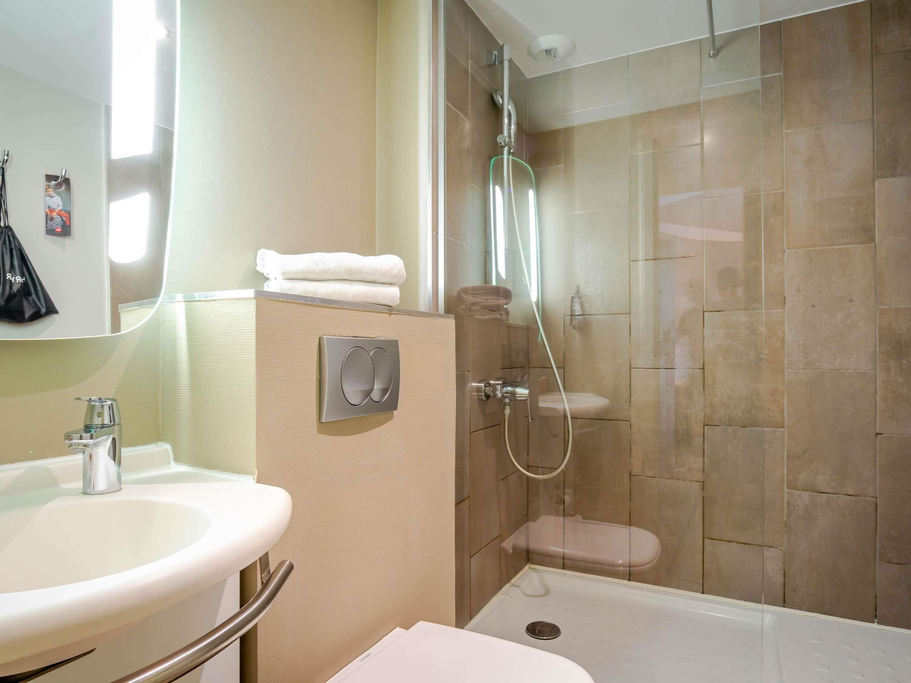 Un baño con lavamanos, inodoro y zona de ducha con mampara de vidrio.