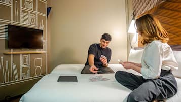 A hotel room with a bed, a television, and a wall with a geometric design.