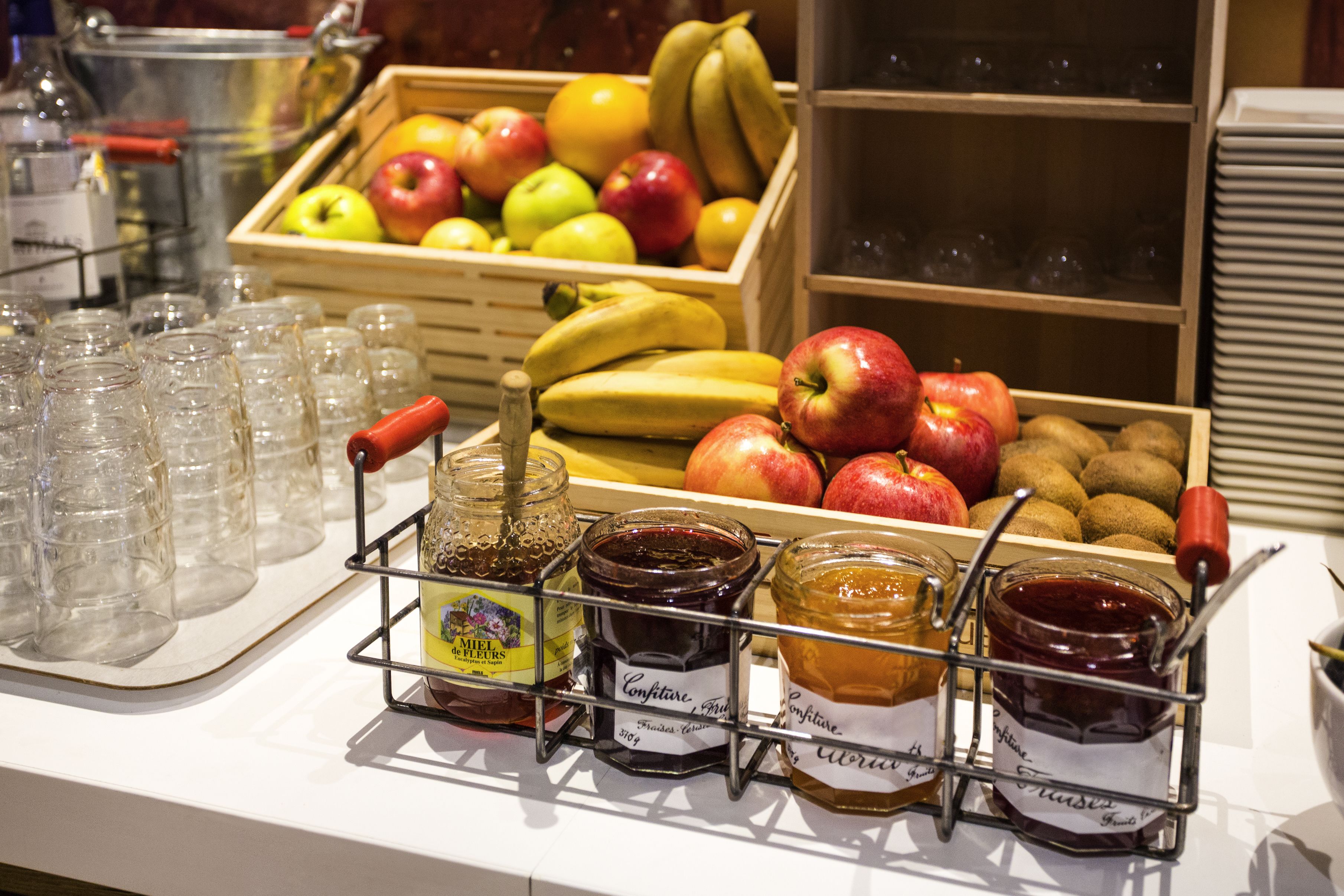 Une présentation de fruits et de confitures, avec un présentoir à verres.