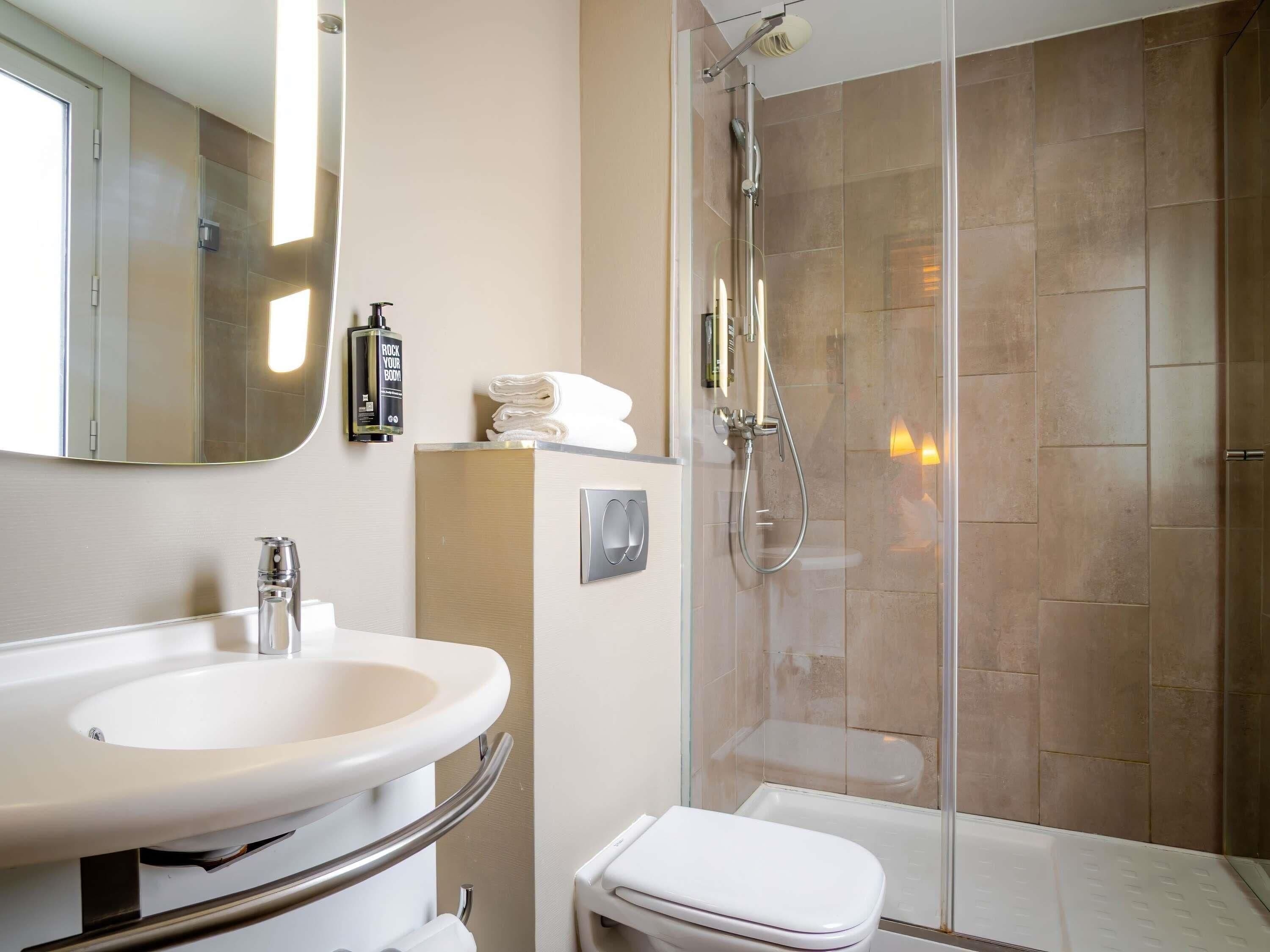 A bathroom with a sink, mirror, towel rack, and shower.