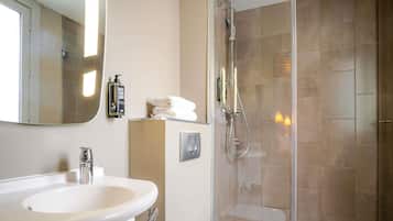 A bathroom with a sink, mirror, towel rack, and shower.