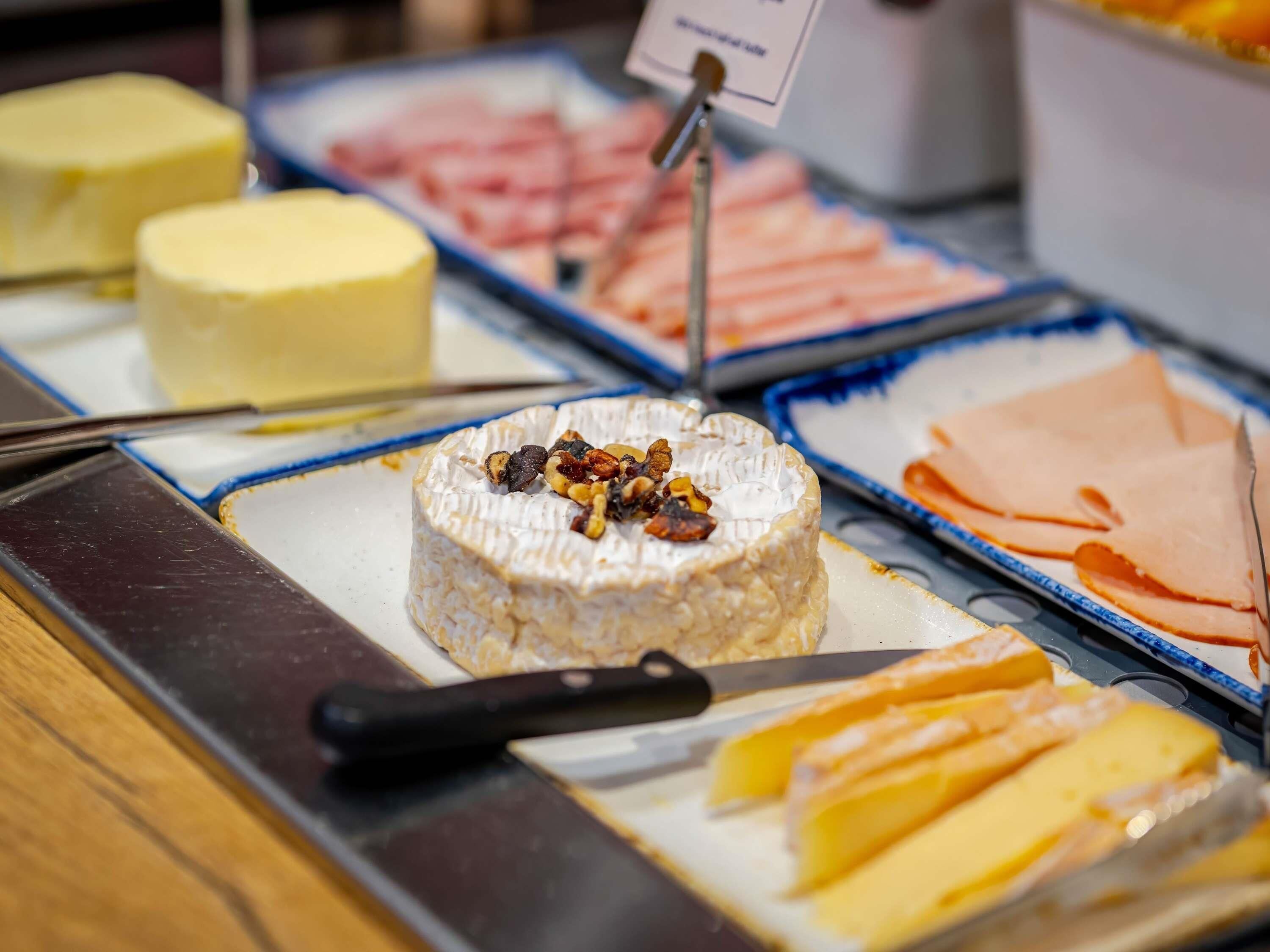 A cheese board with various cheeses, nuts, and a knife.