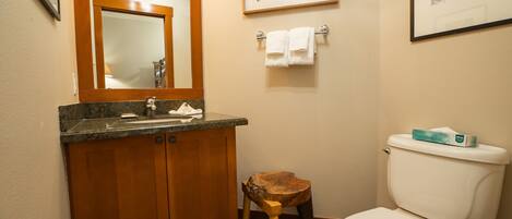 A bathroom with a wooden vanity, a toilet, and a framed picture on the wall.