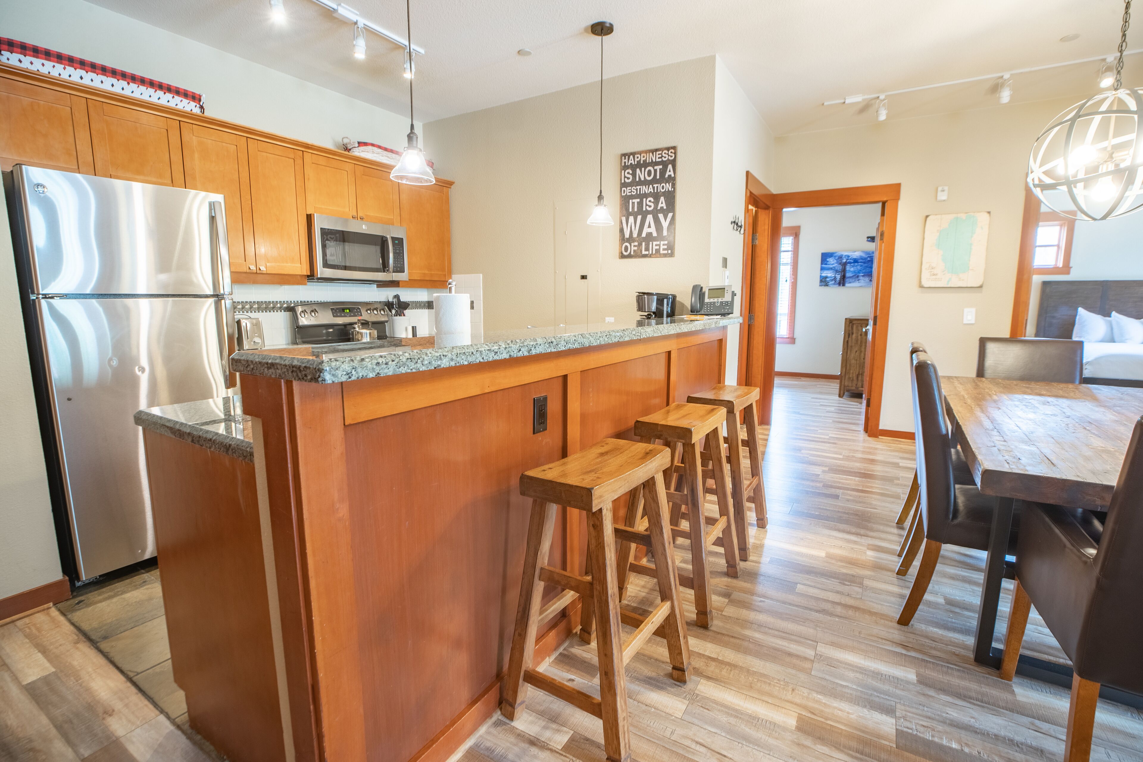 A modern kitchen with wooden cabinets, stainless steel appliances, and a central island with stools.