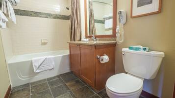 A bathroom with a bathtub, toilet, vanity with a mirror, and a shower.