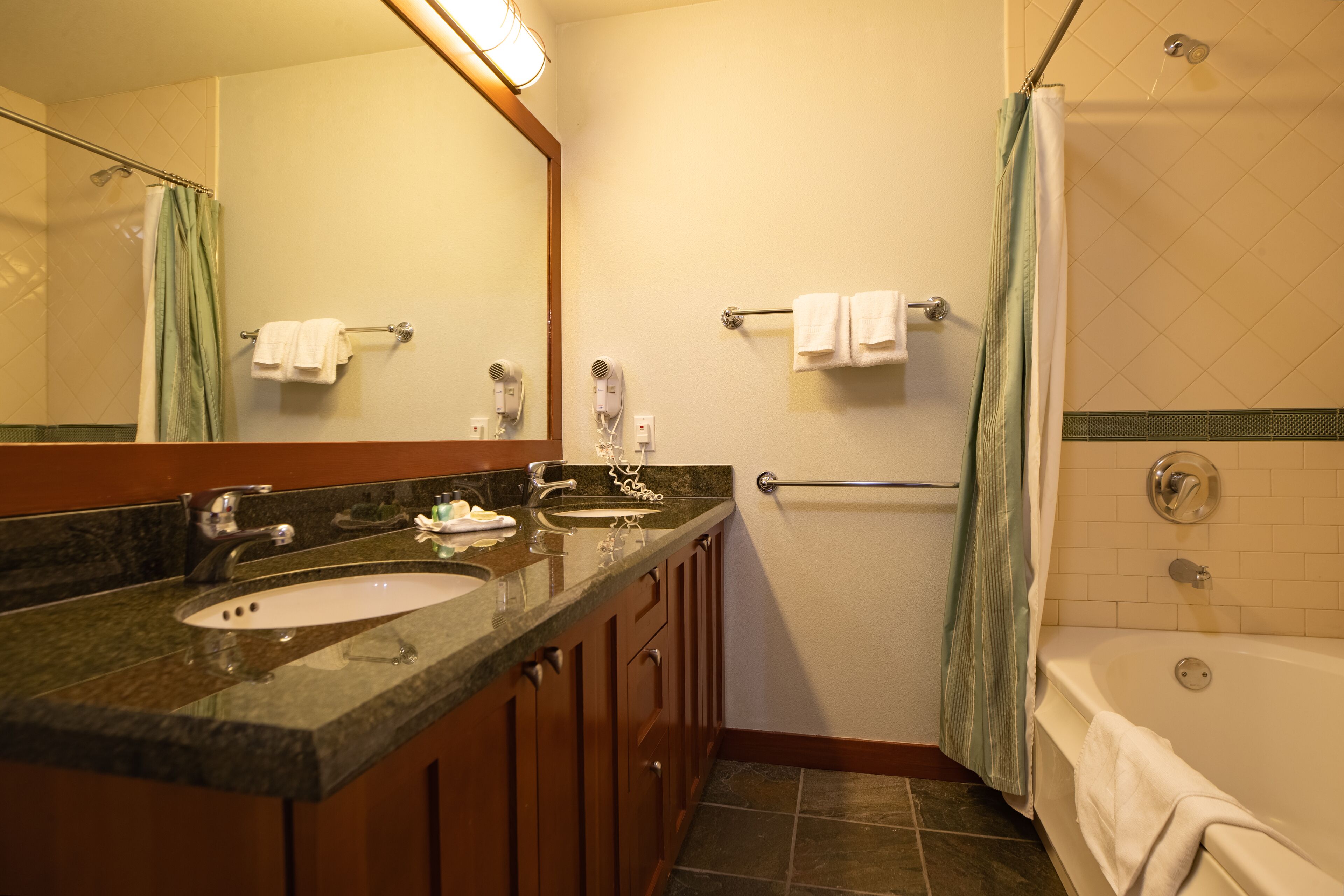 A bathroom with a double sink, a mirror, a towel rack, a shower, and a bathtub.