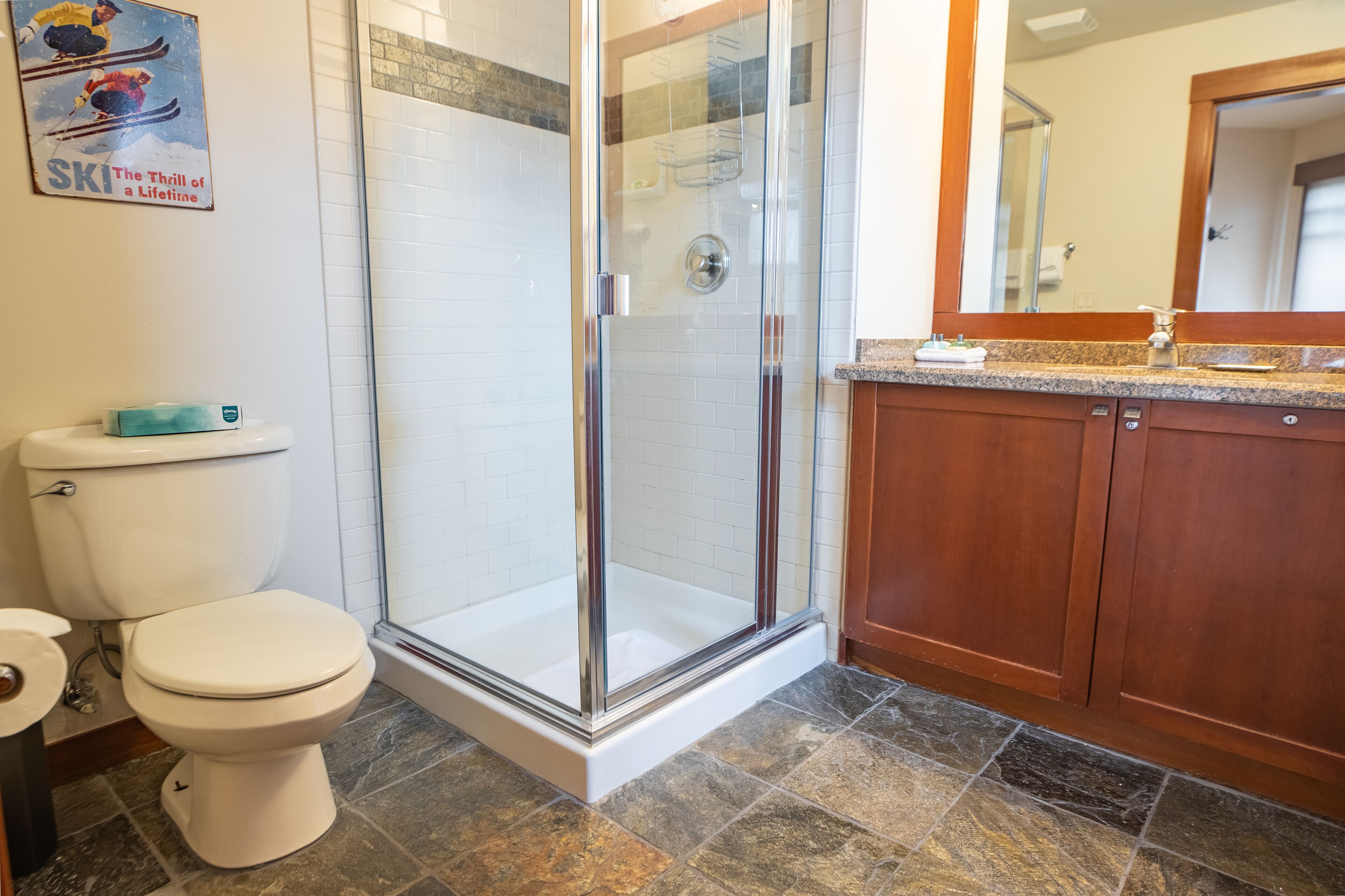 Une salle de bain avec une douche à parois de verre, des toilettes et des meubles en bois.