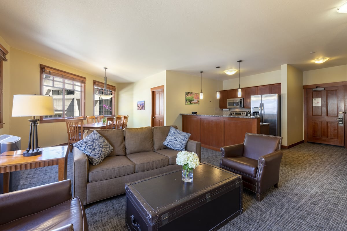 A living room with a sofa, armchairs, a coffee table, and a dining area with chairs and a table.