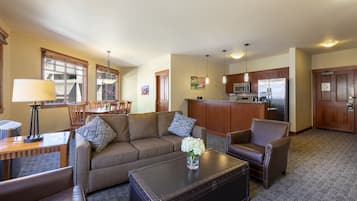 A living room with a sofa, armchairs, a coffee table, and a dining area with chairs and a table.
