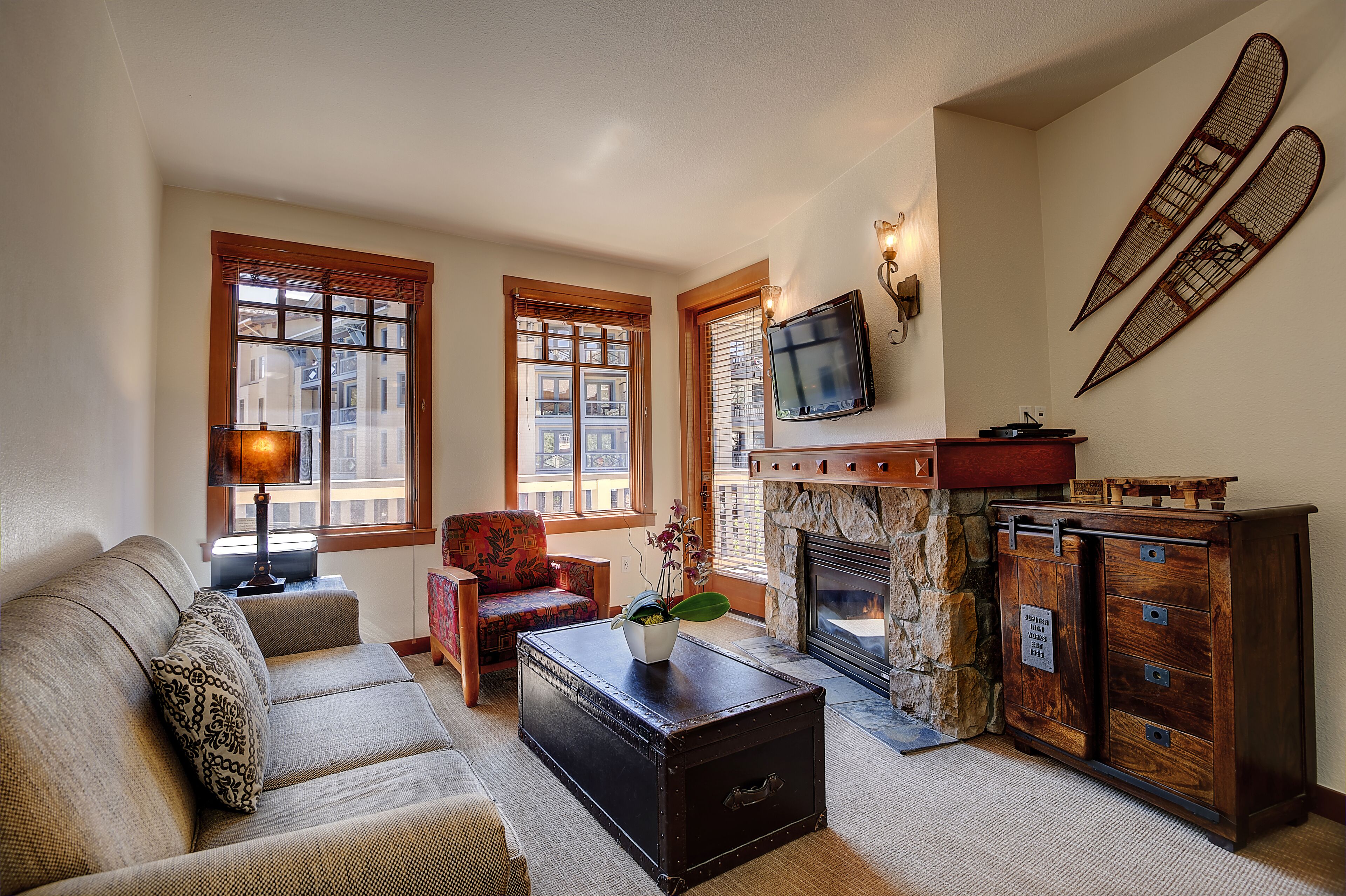 A cozy living room with a sofa, a coffee table, a fireplace, and a television mounted on the wall.