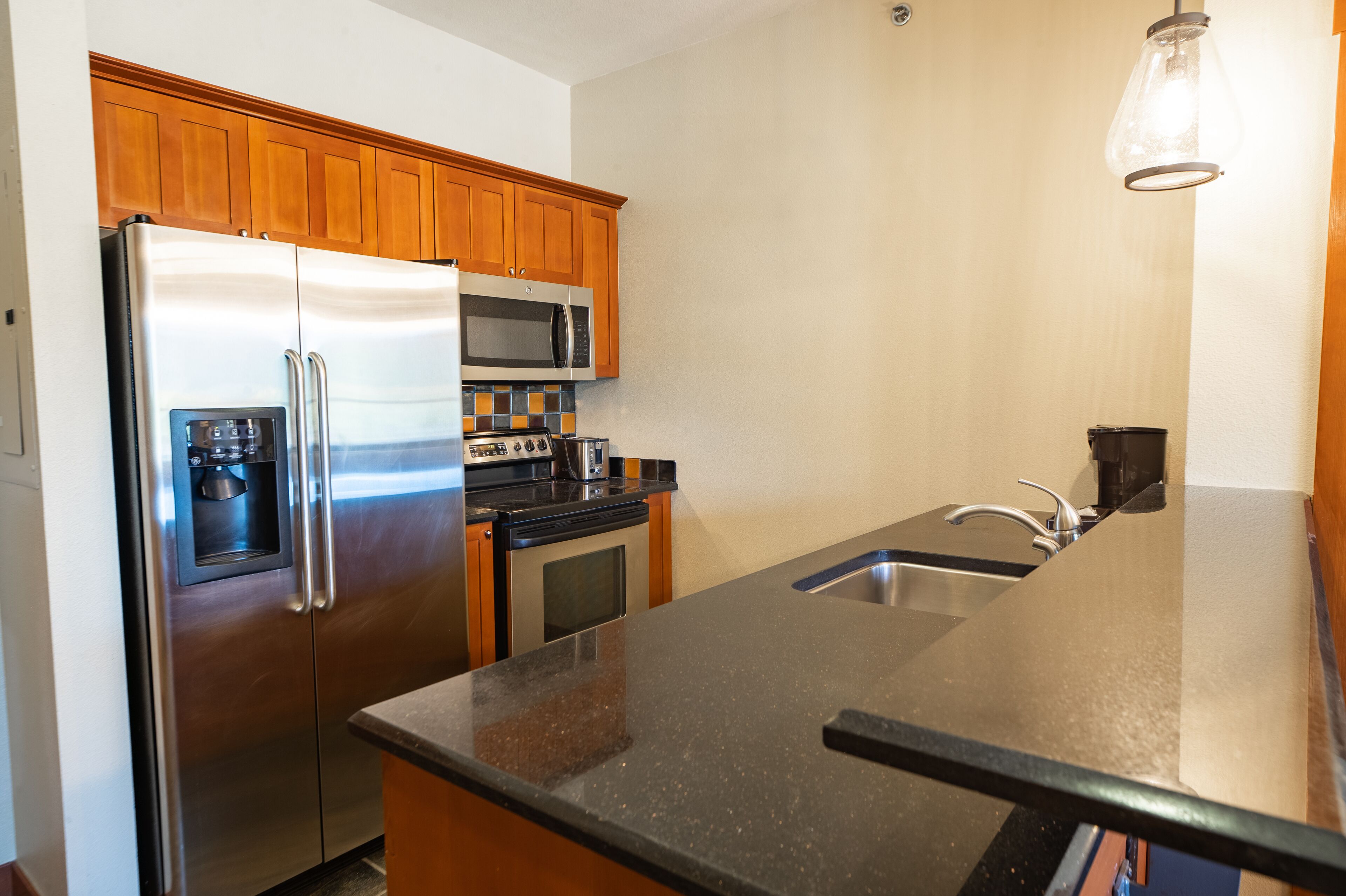A kitchen with stainless steel appliances, wooden cabinets, and a granite countertop.