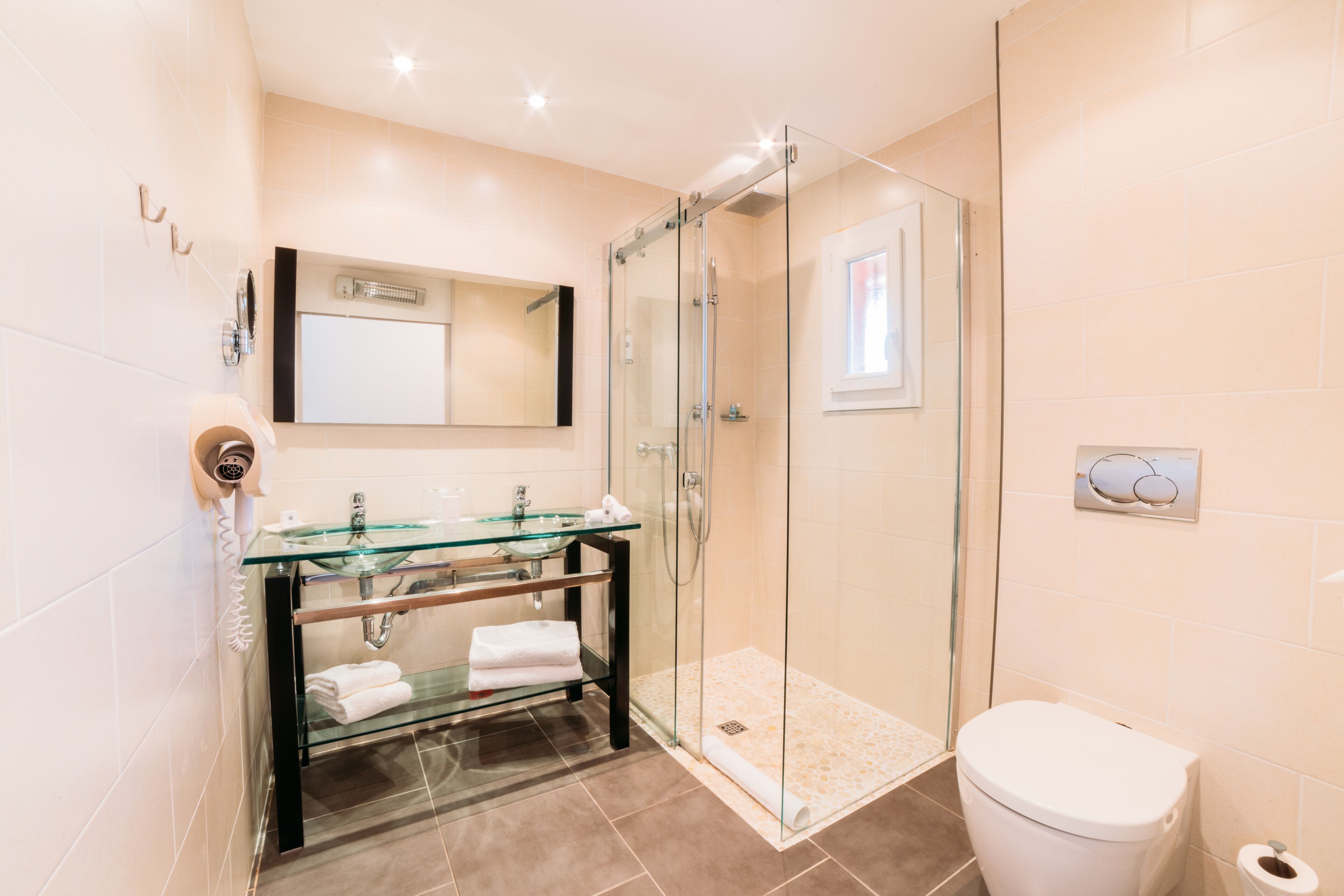 A modern bathroom with a glass shower enclosure, a glass sink, and a toilet.