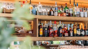 Um bar com várias prateleiras de garrafas de bebidas e copos.