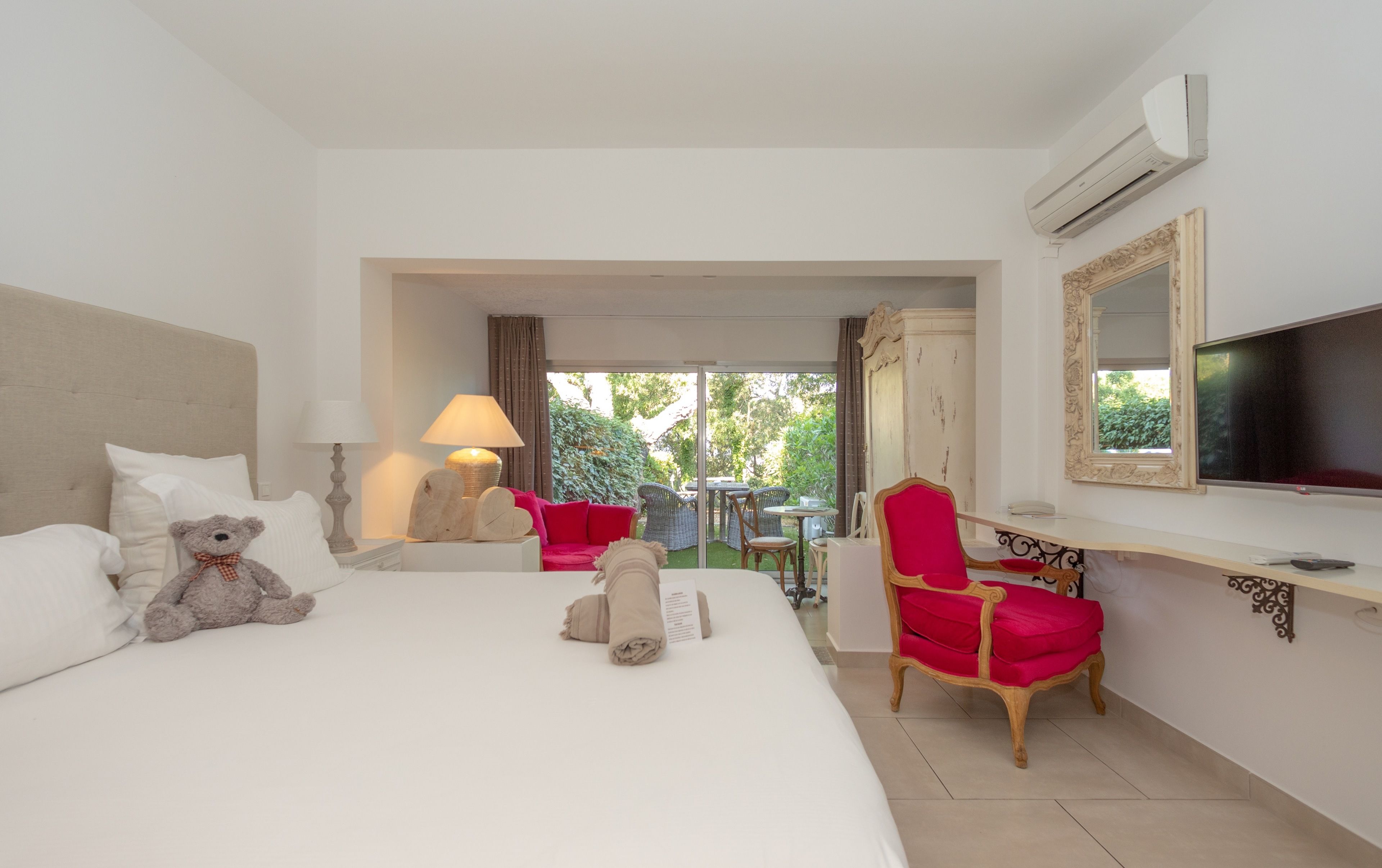 A hotel room with a bed, a chair, a TV, and a view of the outdoors.
