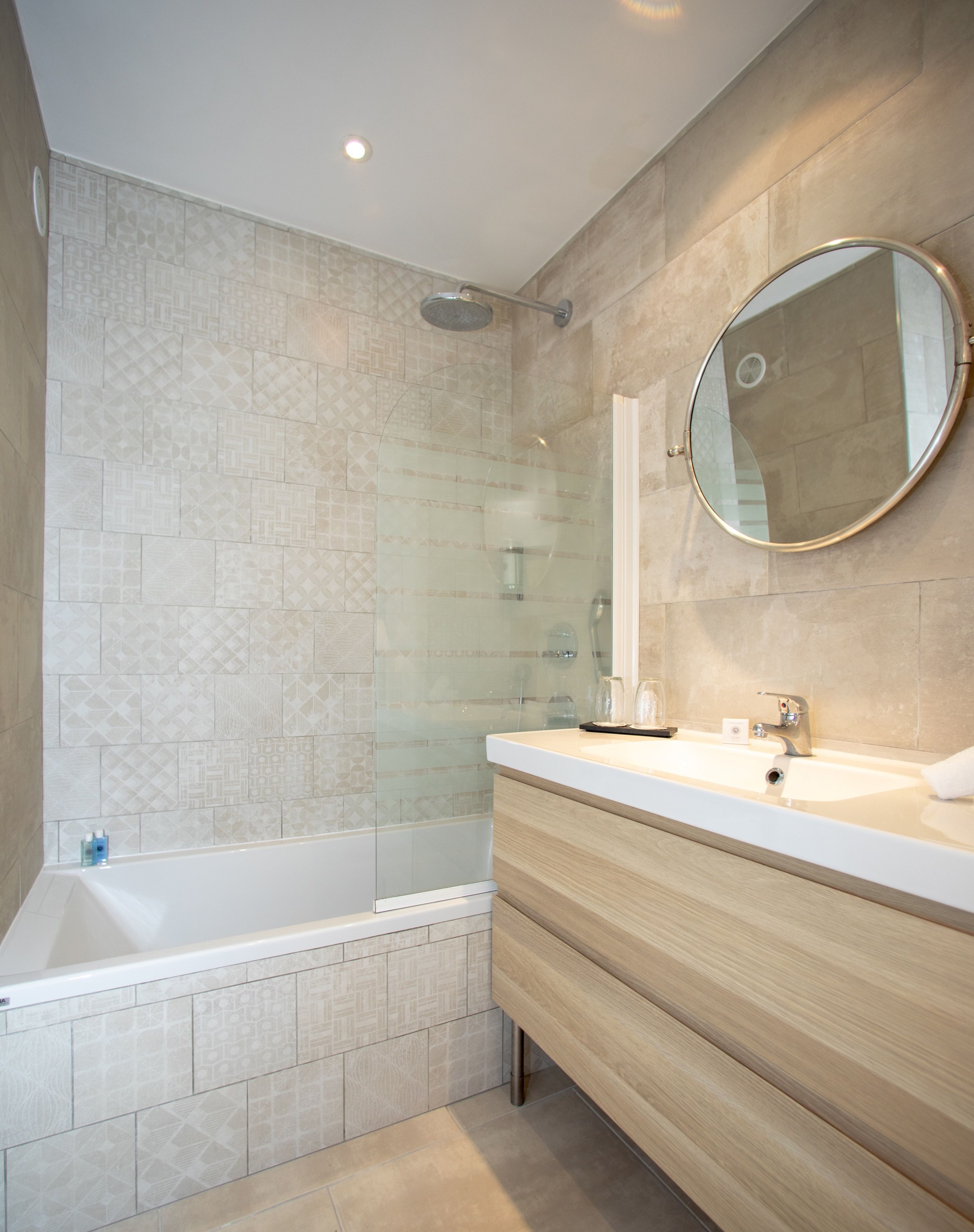 A modern bathroom with a glass-enclosed shower, a wooden vanity, and a large mirror.