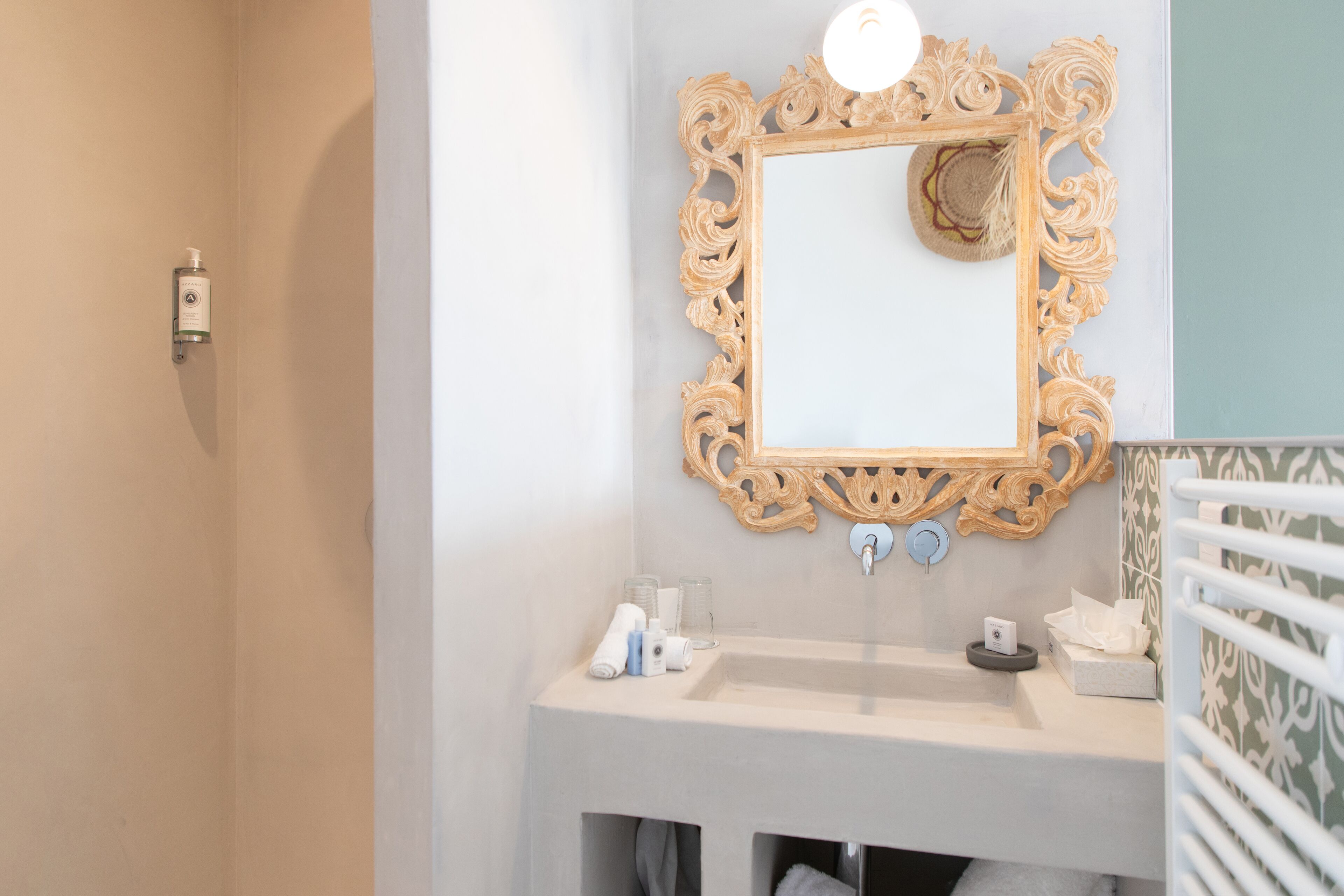A bathroom with a large ornate mirror, a sink, and a towel rack.