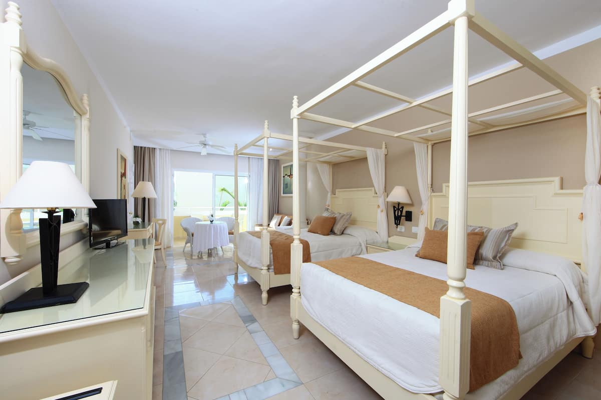 A four-poster bed with a canopy, a bedside table with a lamp, and a large mirror.