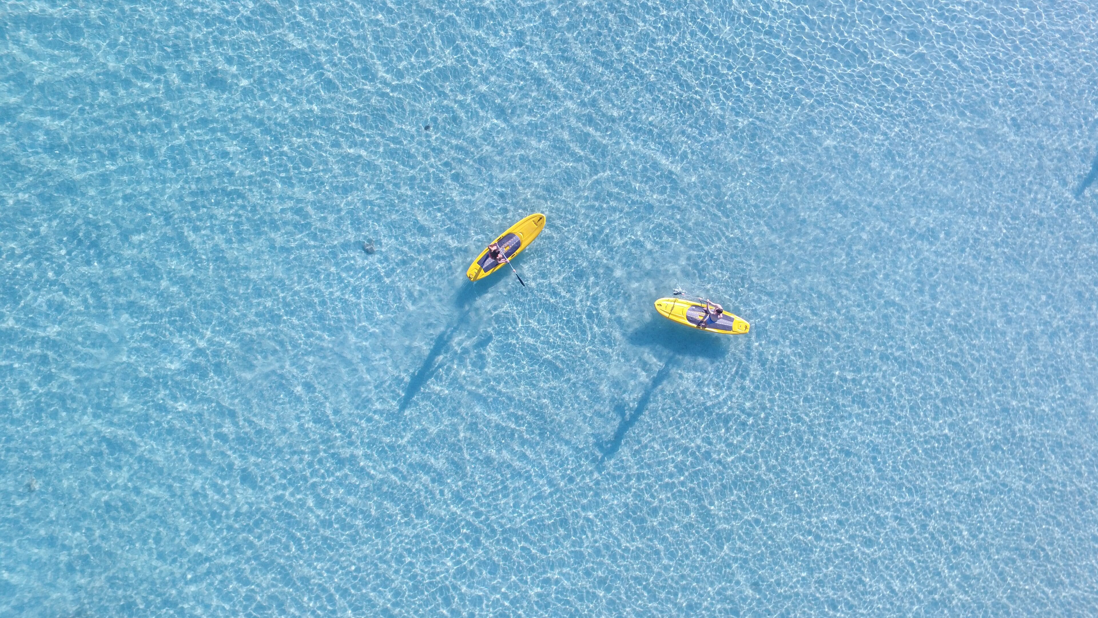 Two yellow paddleboards on a clear blue water surface.