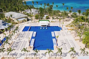 Un resort con piscina central, tumbonas y palmeras.
