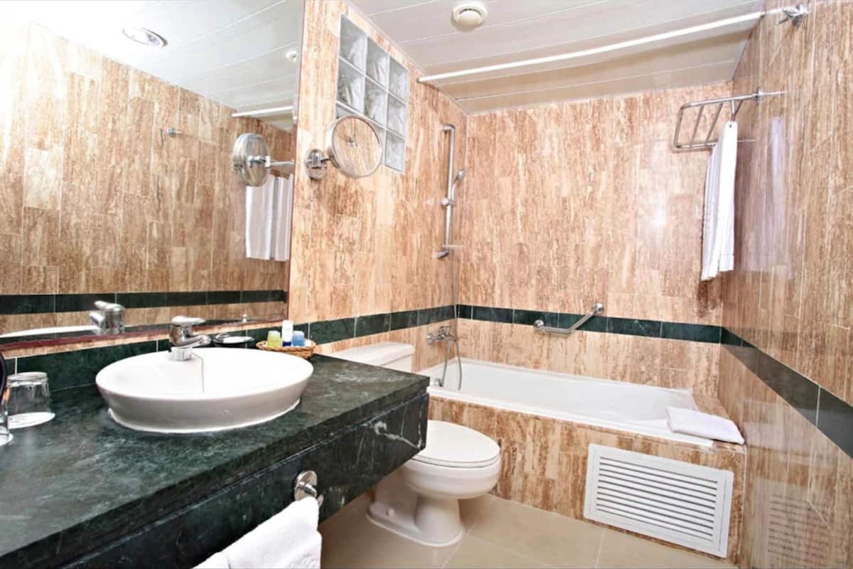 A bathroom with a marble sink, toilet, and bathtub.