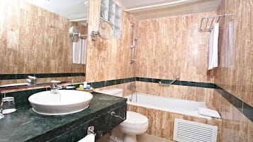 Un baño con lavamanos, inodoro y bañera de mármol.