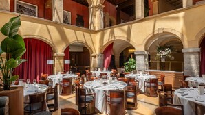A spacious courtyard with multiple round tables set for dining, surrounded by arches and stone walls. - Cour des Loges Lyon, A Radisson Collection Hotel (Lyon)