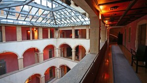 A multi-level atrium with a glass ceiling, multiple arches, and a long corridor with seating.