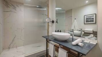 A modern bathroom with a large mirror, a white sink, and a glass shower enclosure.