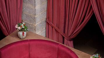 A red upholstered sofa, a round table with a black marble top, and a vase with flowers.