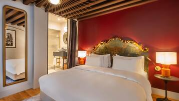 A bedroom with a large bed, a mirror, a red accent wall, and a ceiling fan.