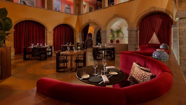 A spacious interior with multiple dining areas, red curtains, and a central seating area with a red sofa.