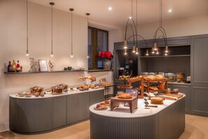 Una cocina moderna con una isla central, diversos alimentos y una ventana con flores rojas.