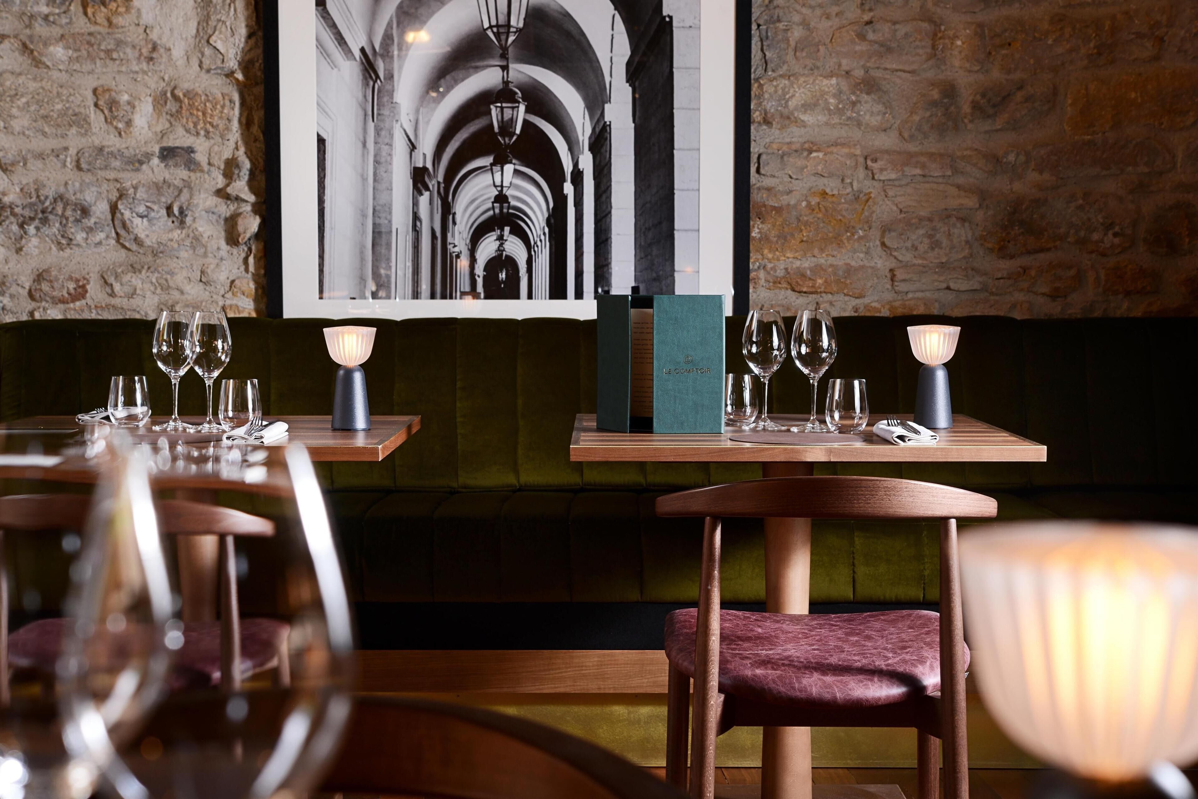 A restaurant interior with wooden tables, chairs, and candlelit lamps.