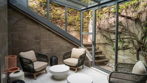 A modern interior with wicker furniture, a glass ceiling, and a stone wall. - Cour des Loges Lyon, A Radisson Collection Hotel (Lyon)