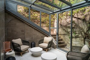 Un interior moderno con mobiliario de mimbre, techo de cristal y pared de piedra.