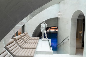 A modern interior with a marble statue, a pool, and a staircase.