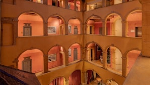 A multi-level atrium with a glass ceiling, multiple balconies, and arched walkways.