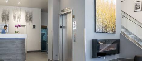 A modern reception area with a reception desk, a fireplace, and a staircase.
