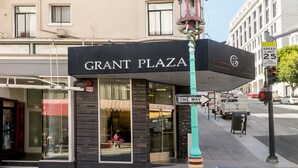 A building with a sign reading "GRANT PLAZA" and a "SCHOOL SPEED LIMIT 25" sign. - Grant Plaza Hotel (San Francisco)