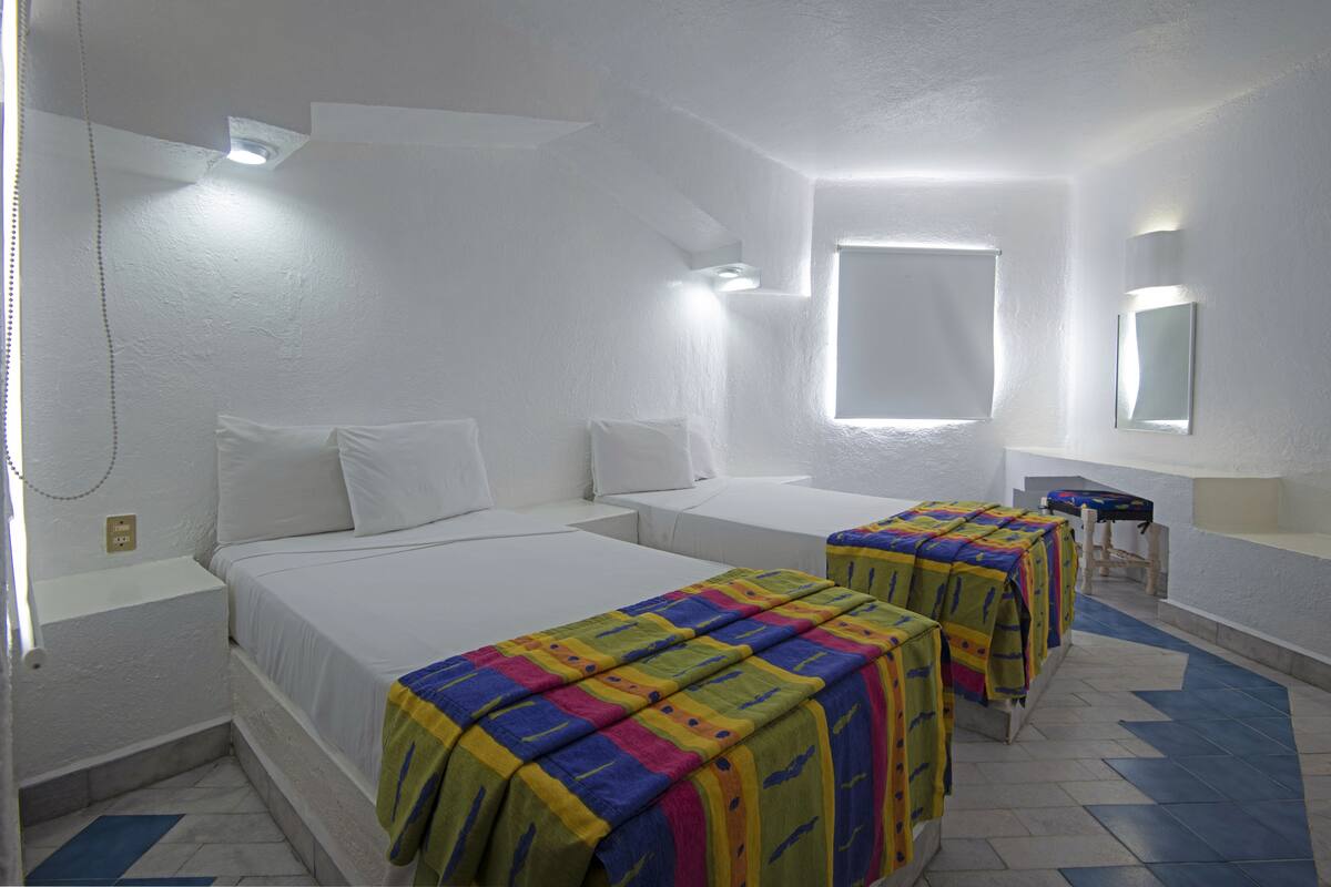 A hotel room with two beds, a window, and a small table.