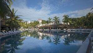 A pool with lounge chairs and palm trees, surrounded by buildings and a clear sky. - Gran Festivall Resort (Manzanillo)