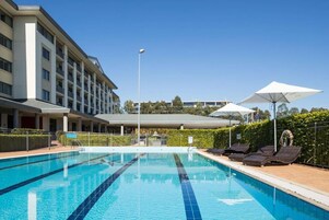 Una piscina al aire libre, sillones reclinables de piscina